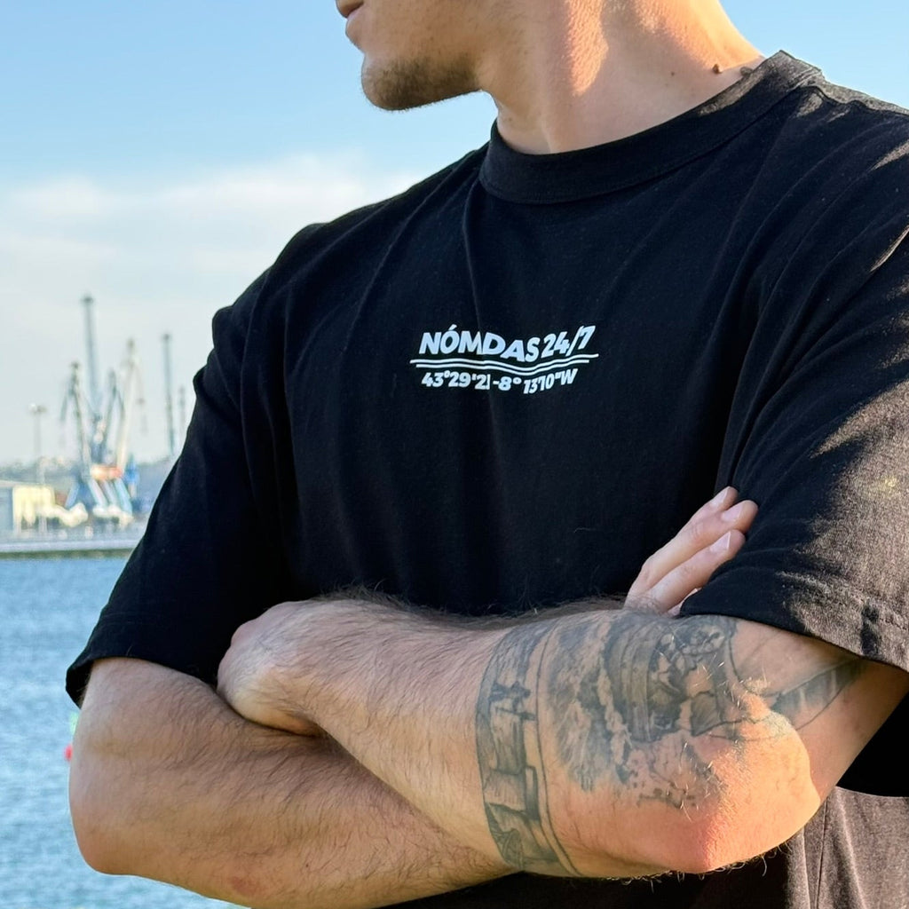 Modelo con camiseta negra Ferrol Classic de Nómadas 24/7 en el puerto de Ferrol